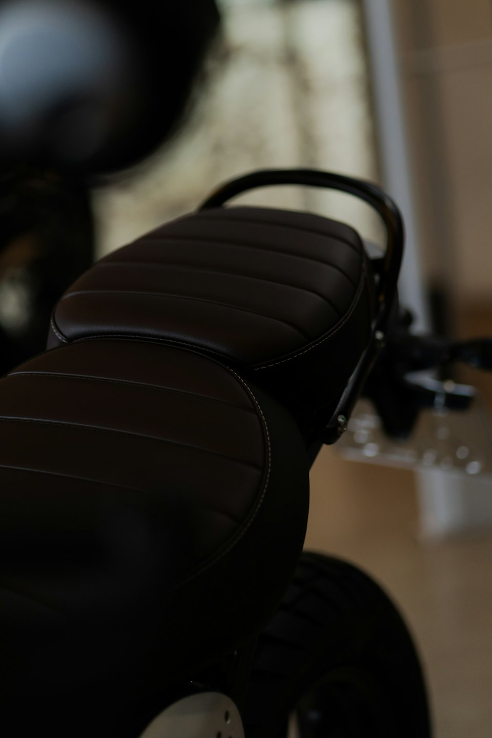 Dark brown leather motorcycle seat with ribbed cushioning and stitching.
