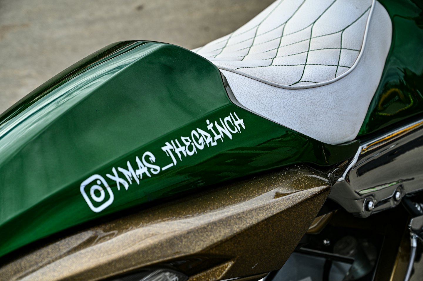 Custom motorcycle with a green body and quilted leather seat.
