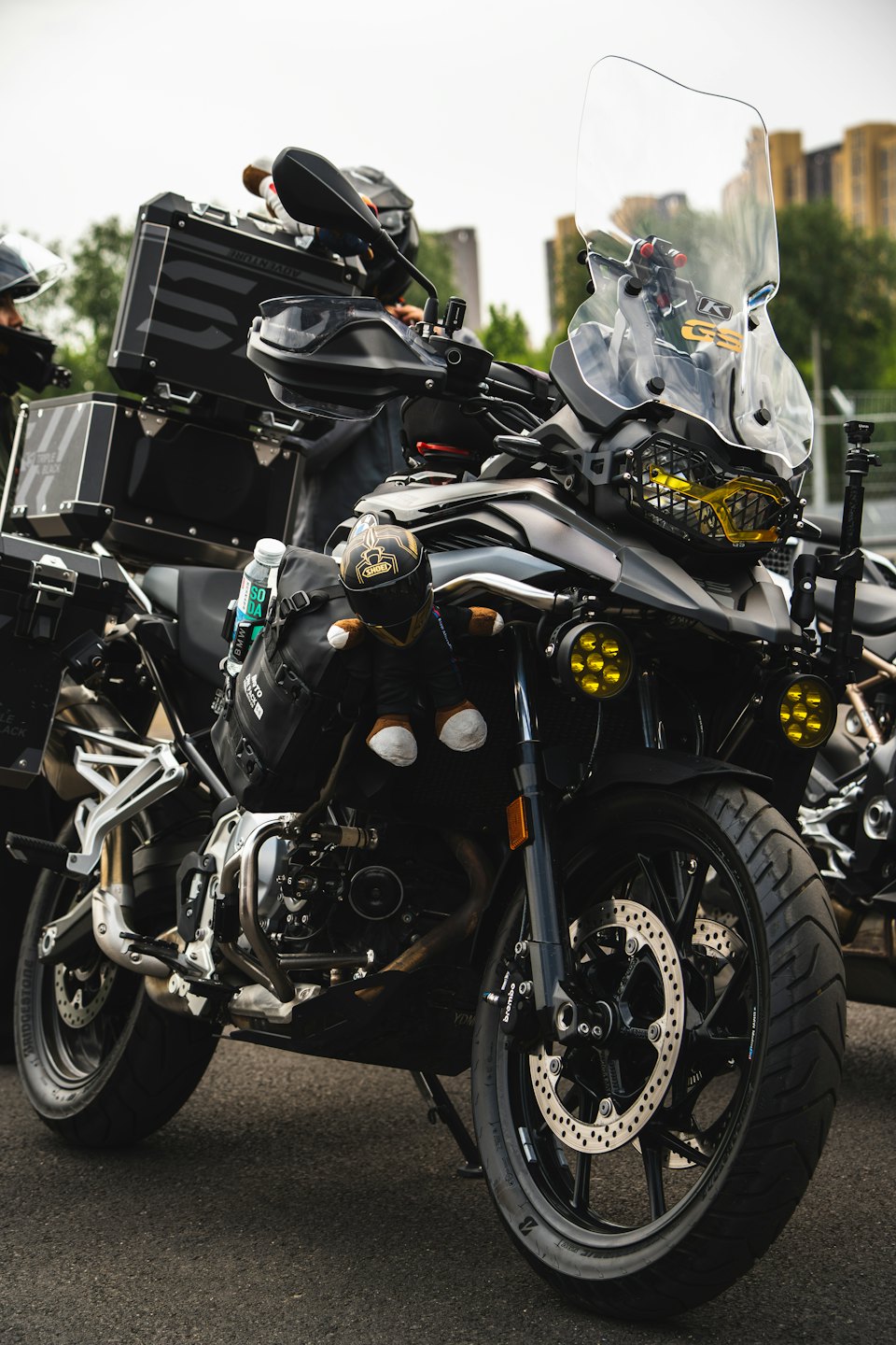 Adventure touring motorcycle with storage cases and mascot parked outdoors.