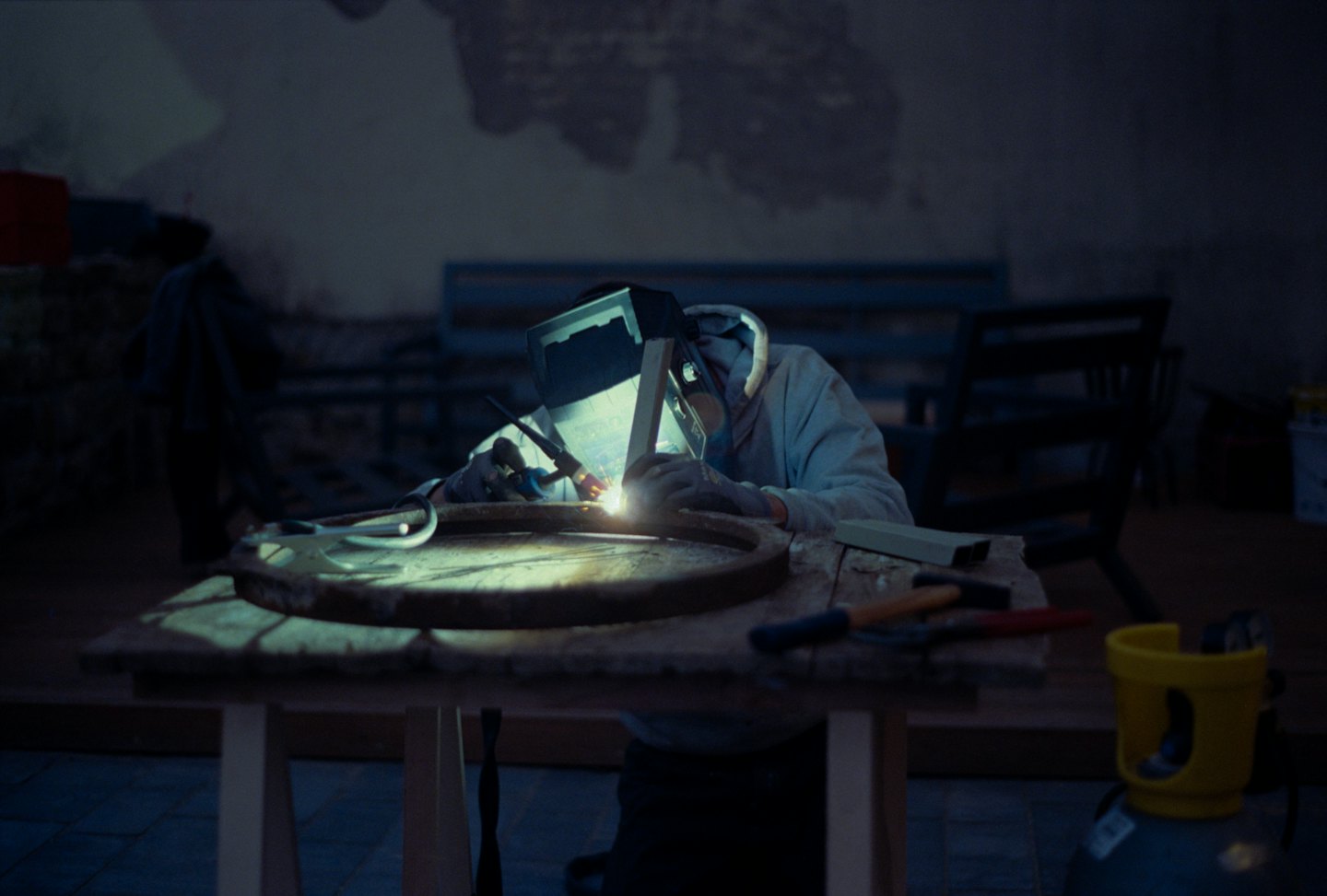 Craftsperson welds metal ring in a workshop.
