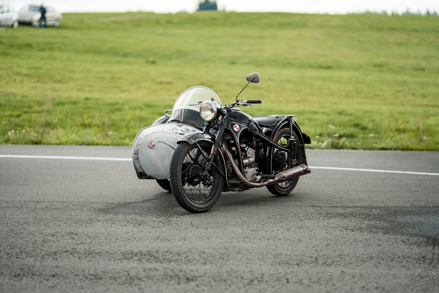 Vintage black motorcycle with a grey sidecar parked on an asphalt road.
